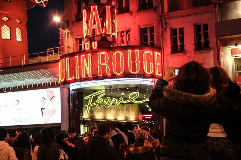 De toeristen die beelden voor Moulin-Rouge nemen bij nacht, één van het beroemdste Pigalle-cabaret en tonen agenten van Parisi stock fotografie De toeristen die beelden voor Moulin-Rouge nemen bij nacht, één van het beroemdste Pigalle-cabaret en tonen agenten van Parisi stock fotografie