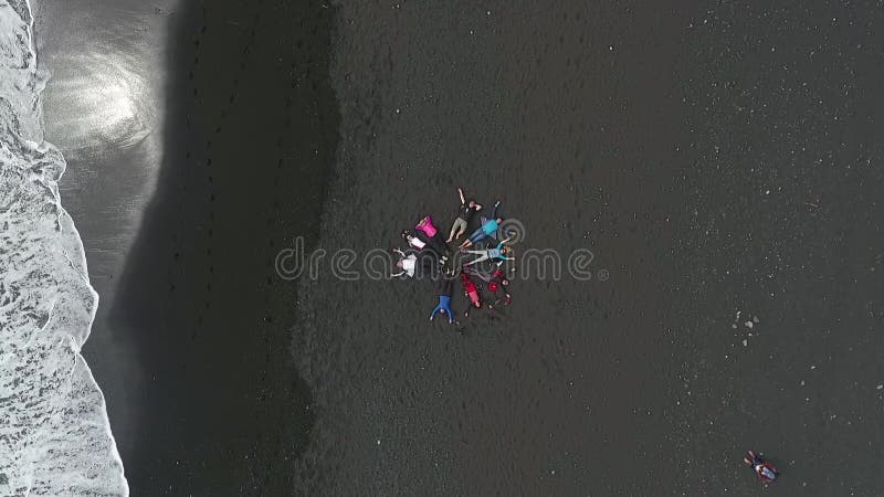 De toeristen liggen calmly op het zwarte zand op de oceaankust Andreev