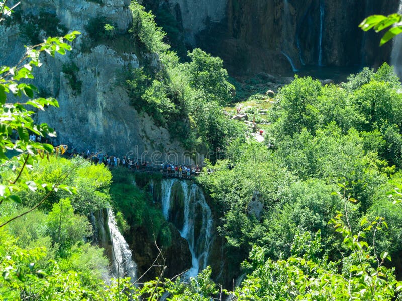 De toeristen lopen op een hangbrug dichtbij de waterval in Plitvice, Kroatië royalty-vrije stock fotografie De toeristen lopen op een hangbrug dichtbij de waterval in Plitvice, Kroatië royalty-vrije stock fotografie