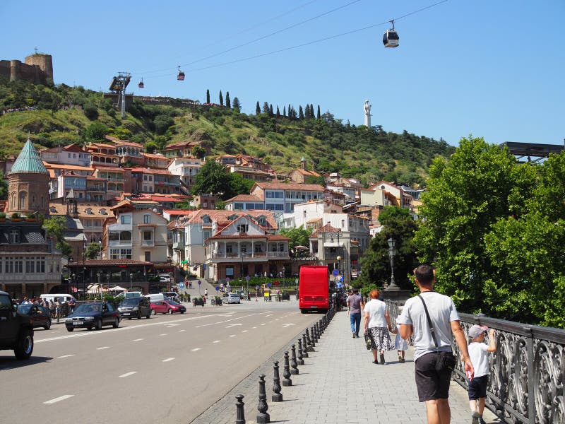De toeristen met families lopen op de brug in het centrum van oud Tbilisi om de gezichten te zien Georgië, Tbilisi - Juni 2019 stock fotografie De toeristen met families lopen op de brug in het centrum van oud Tbilisi om de gezichten te zien Georgië, Tbilisi - Juni 2019 stock fotografie