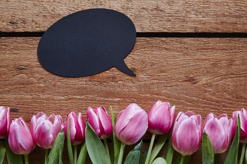 De toespraakbel van het de lentebericht en verse tulpen op hout royalty-vrije stock afbeeldingen De toespraakbel van het de lentebericht en verse tulpen op hout royalty-vrije stock afbeeldingen
