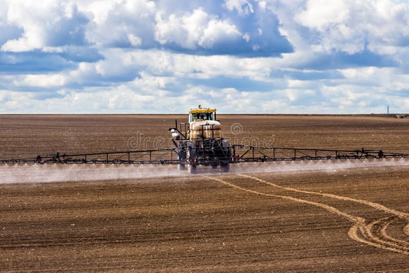 De tractor die een gebied op landbouwbedrijf bespuiten, bevrucht het land royalty-vrije stock fotografie De tractor die een gebied op landbouwbedrijf bespuiten, bevrucht het land royalty-vrije stock fotografie