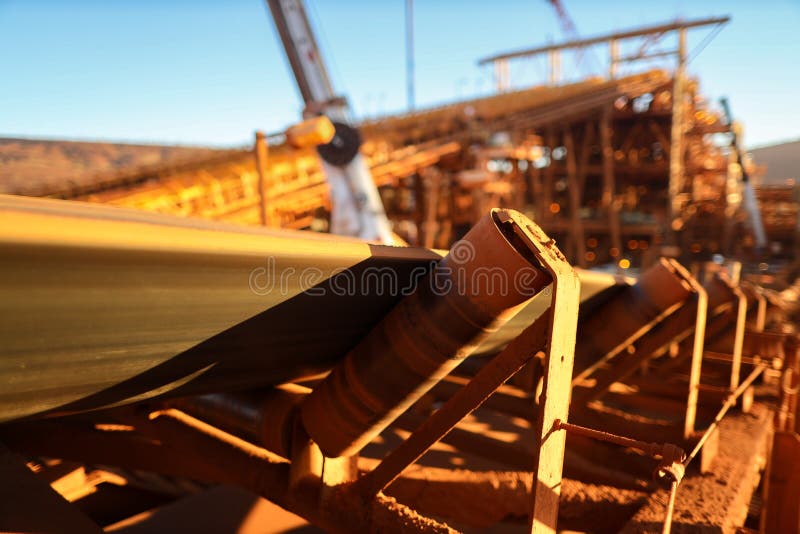 De transportband en de rollen structureren lijn zijn overdrachtijzererts in de materiële plaats van de de bouwmijn van het het sc stock afbeelding De transportband en de rollen structureren lijn zijn overdrachtijzererts in de materiële plaats van de de bouwmijn van het het sc stock afbeelding