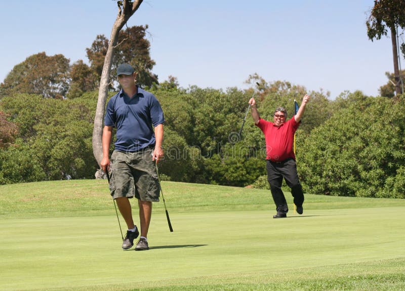 Senior Golfer performing happy dance after defeating younger golfer as they walk off putting green. Senior Golfer performing happy dance after defeating younger golfer as they walk off putting green