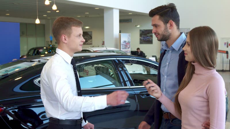 De verkoper geeft de autosleutel aan het paar bij het handel drijven