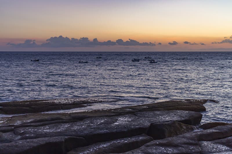 De verlaten vissersboten die in het overzees tijdens zonsondergang langs de rotsachtige kust van La Caleta, Costa Adeje op Teneri stock afbeelding De verlaten vissersboten die in het overzees tijdens zonsondergang langs de rotsachtige kust van La Caleta, Costa Adeje op Teneri stock afbeelding