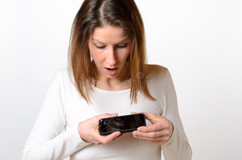 De verraste vrouw bekijkt neer gebroken mobiele telefoon stock afbeelding De verraste vrouw bekijkt neer gebroken mobiele telefoon stock afbeelding