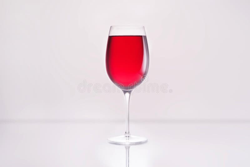 de verre complètement du vin rouge sur la surface réfléchissante