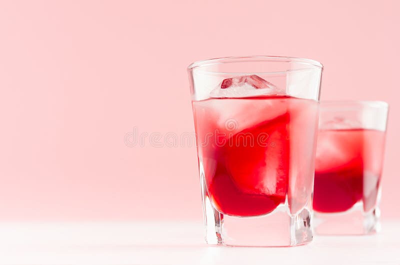 De verse koude rode cocktails van het de zomerfruit met ijsblokjes in elegant modern keukenbinnenland in lichte zachte pastelkleu stock foto De verse koude rode cocktails van het de zomerfruit met ijsblokjes in elegant modern keukenbinnenland in lichte zachte pastelkleu stock foto