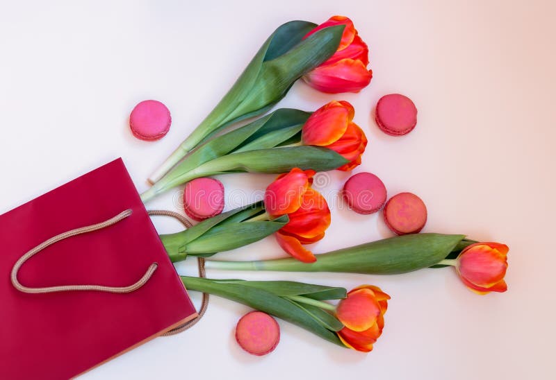 De verse oranje tulp bloeit en roze makarons in document zak op pastelkleurachtergrond royalty-vrije stock afbeeldingen De verse oranje tulp bloeit en roze makarons in document zak op pastelkleurachtergrond royalty-vrije stock afbeeldingen