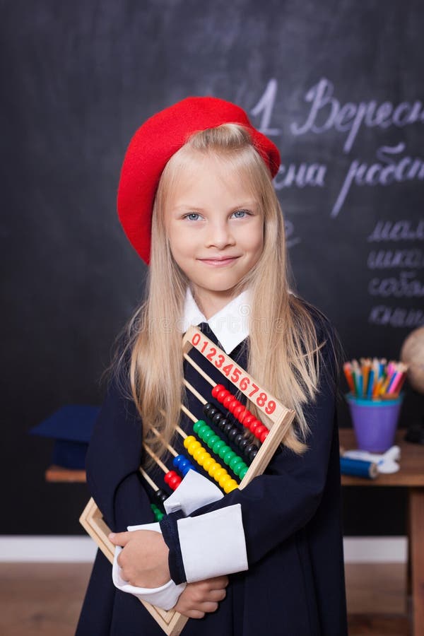 De volta à escola! Suportes alegres da menina com contas Conceito da escola Respostas da estudante na lição A criança está estuda imagem de stock De volta à escola! Suportes alegres da menina com contas Conceito da escola Respostas da estudante na lição A criança está estuda imagem de stock