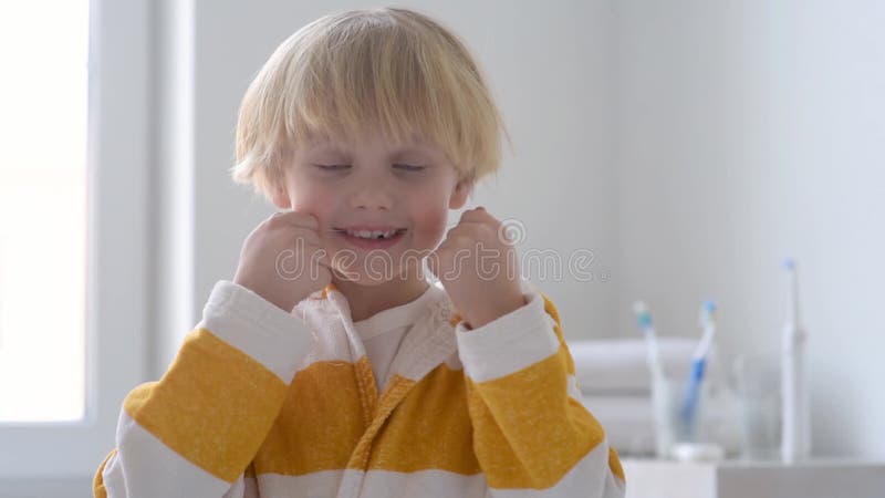 De voorschoolse jongen maakte tanden schoon met tandheelkundig flosmiddel en poetst zijn tanden vervolgens zorgvuldig met tandenbo