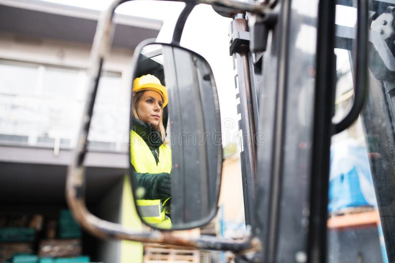 De vrachtwagenchauffeur van de vrouwenvorkheftruck op een industriezone royalty-vrije stock afbeelding De vrachtwagenchauffeur van de vrouwenvorkheftruck op een industriezone royalty-vrije stock afbeelding