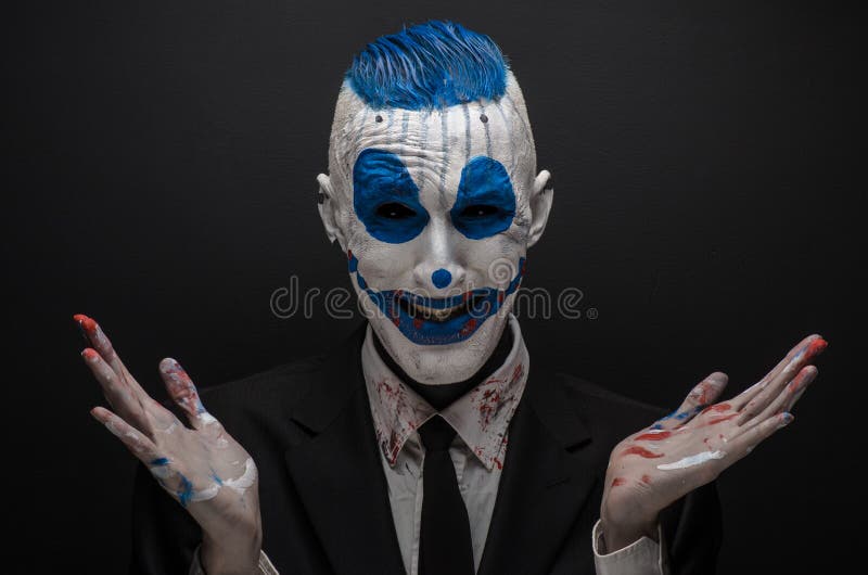 De vreselijke clown en Halloween als thema hebben: Gekke blauwe clown in zwart die kostuum op een donkere achtergrond in de studi royalty-vrije stock afbeelding De vreselijke clown en Halloween als thema hebben: Gekke blauwe clown in zwart die kostuum op een donkere achtergrond in de studi royalty-vrije stock afbeelding