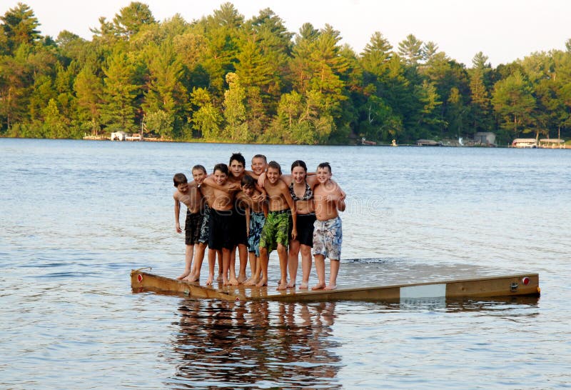 A group of nine kids ages 11-13 on a floating dock in a lake at sumer camp. A group of nine kids ages 11-13 on a floating dock in a lake at sumer camp.