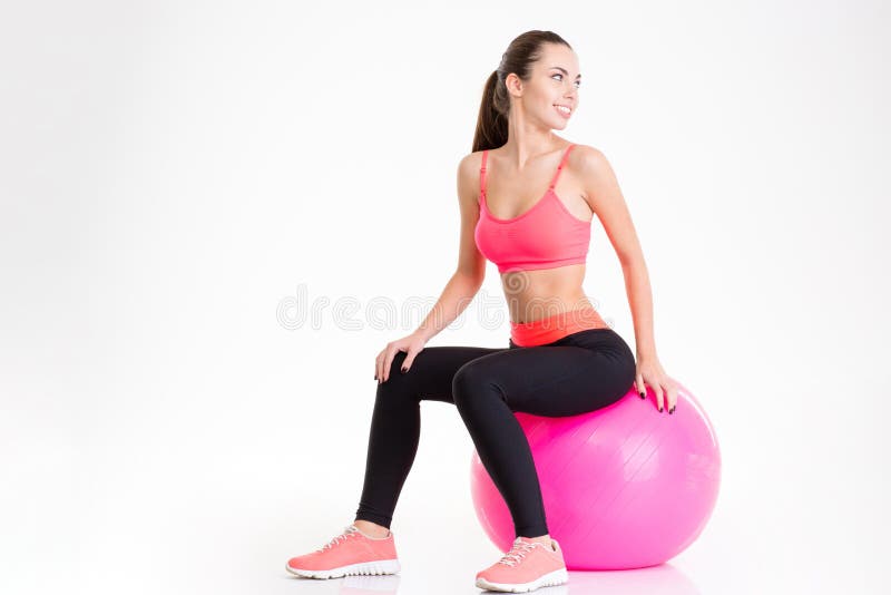 De vrolijke vrij jonge zitting van de geschiktheidsvrouw op roze fitball stock foto's De vrolijke vrij jonge zitting van de geschiktheidsvrouw op roze fitball stock foto's