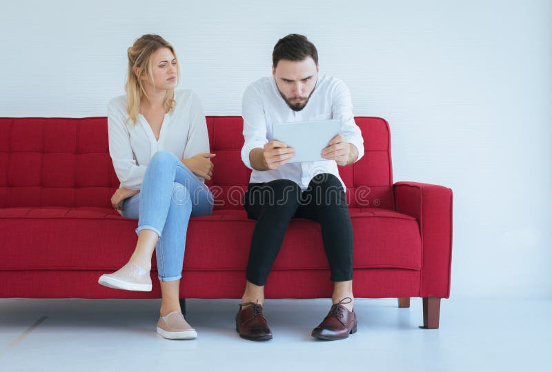 De vrouw bored en veronachtzaming samen aan man zitting op laag in woonkamer, het concept van Familiekwesties stock afbeeldingen De vrouw bored en veronachtzaming samen aan man zitting op laag in woonkamer, het concept van Familiekwesties stock afbeeldingen