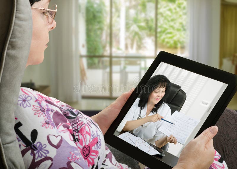 Mature adult women consults a e-health doctor with tablet computer sitting in soft chair. In touchscreen, female doctor in white uniform reviewing blood pressure report. With telehealth application patient can reach relevant specialist remotely. Horizontal e shot on indoors blurred background. Mature adult women consults a e-health doctor with tablet computer sitting in soft chair. In touchscreen, female doctor in white uniform reviewing blood pressure report. With telehealth application patient can reach relevant specialist remotely. Horizontal e shot on indoors blurred background