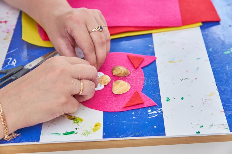 De vrouw creeert een kat van rood en overzeese shells op de workshop wordt gevoeld die royalty-vrije stock fotografie De vrouw creeert een kat van rood en overzeese shells op de workshop wordt gevoeld die royalty-vrije stock fotografie