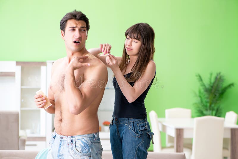 De vrouw die het pleister van het pepercapsicum toepassen op echtgenoot om pijn te verlichten stock fotografie De vrouw die het pleister van het pepercapsicum toepassen op echtgenoot om pijn te verlichten stock fotografie