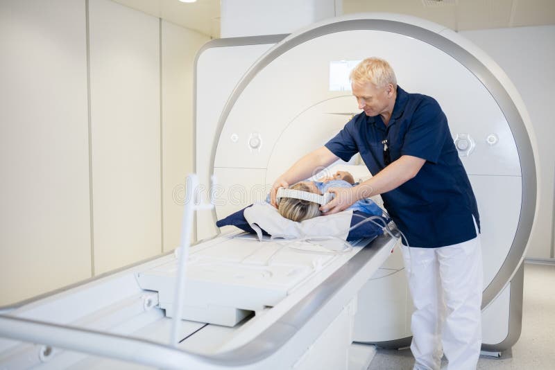 De Vrouw die van radiologenputting headphones on MRI-Aftasten ondergaan royalty-vrije stock foto De Vrouw die van radiologenputting headphones on MRI-Aftasten ondergaan royalty-vrije stock foto