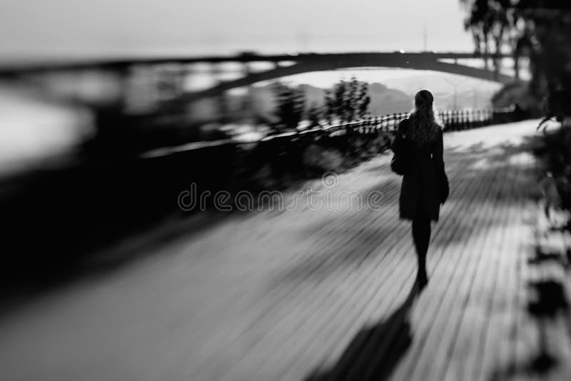 Een vrouw loopt over een lange afstand op de weg stock afbeelding