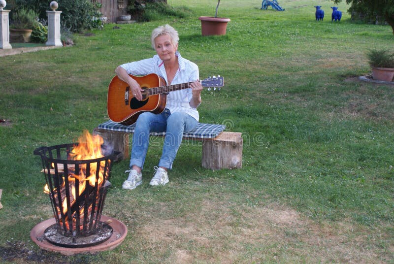 De vrouw is gelukkig over de aardige avond en speelt op de gitaar royalty-vrije stock foto's De vrouw is gelukkig over de aardige avond en speelt op de gitaar royalty-vrije stock foto's
