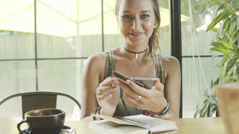 De vrouw is gelukkig voor online het kopen van kleding met smartphone in koffie stock footage De vrouw is gelukkig voor online het kopen van kleding met smartphone in koffie stock footage