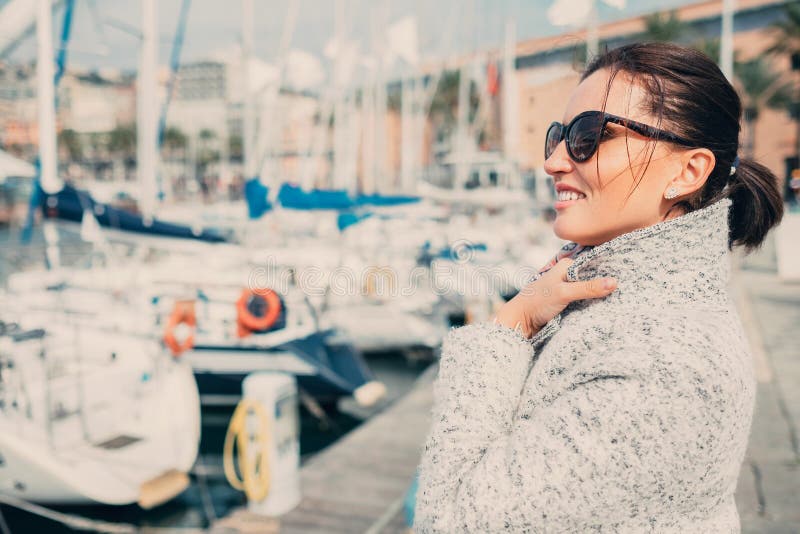 De vrouw geniet van met winderige zonnige de lentedag in de overzeese haven stock foto De vrouw geniet van met winderige zonnige de lentedag in de overzeese haven stock foto