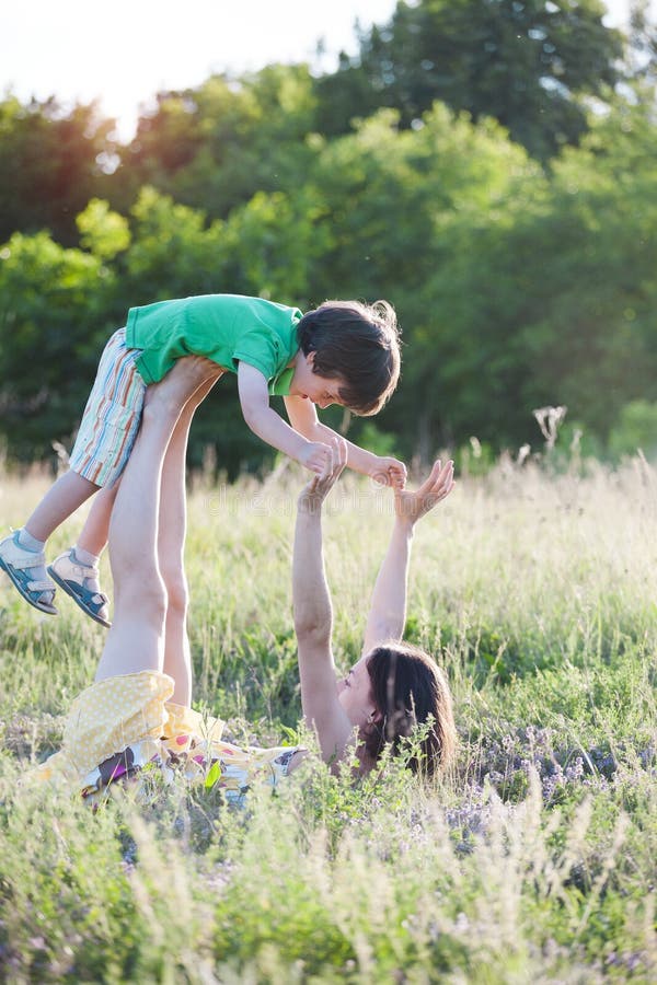 De vrouw heft de baby op haar voeten op stock foto's De vrouw heft de baby op haar voeten op stock foto's