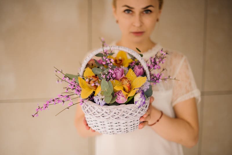 De vrouw houdt een kleine mand met bloemen royalty-vrije stock foto's De vrouw houdt een kleine mand met bloemen royalty-vrije stock foto's