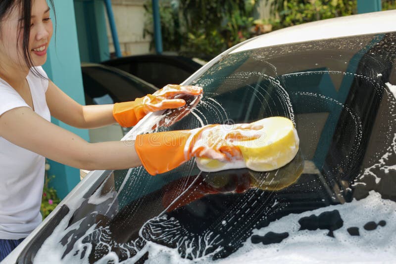 De vrouw houdt microfiber in hand en poetst de auto op stock afbeeldingen De vrouw houdt microfiber in hand en poetst de auto op stock afbeeldingen
