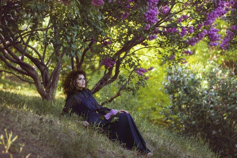 De vrouw rust onder een lilac struik in het park royalty-vrije stock afbeeldingen De vrouw rust onder een lilac struik in het park royalty-vrije stock afbeeldingen