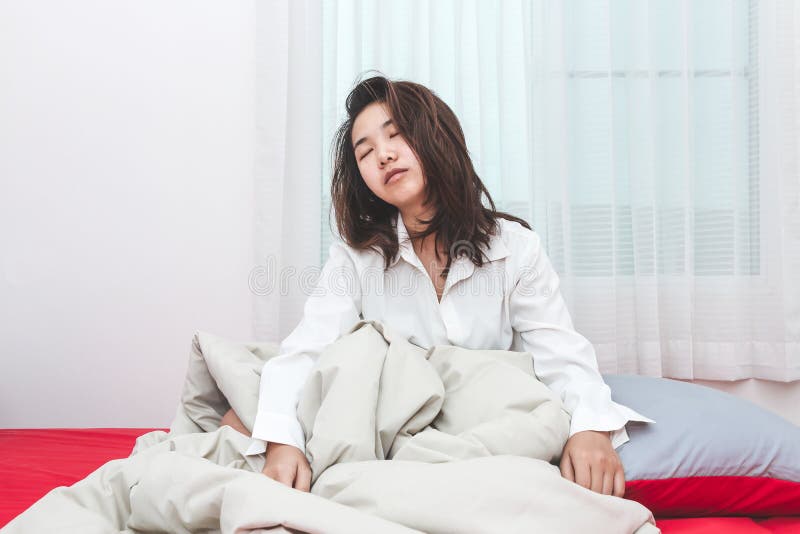 De vrouw van Azië probeert om op de ochtend in haar bedruimte te ontwaken stock foto's De vrouw van Azië probeert om op de ochtend in haar bedruimte te ontwaken stock foto's