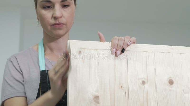 De vrouw in de workshop werkt aan houten raad, die een effect van antiquiteit creëren