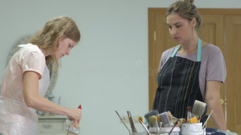 De vrouw in de workshop werkt aan houten raad, die een effect van antiquiteit creëren