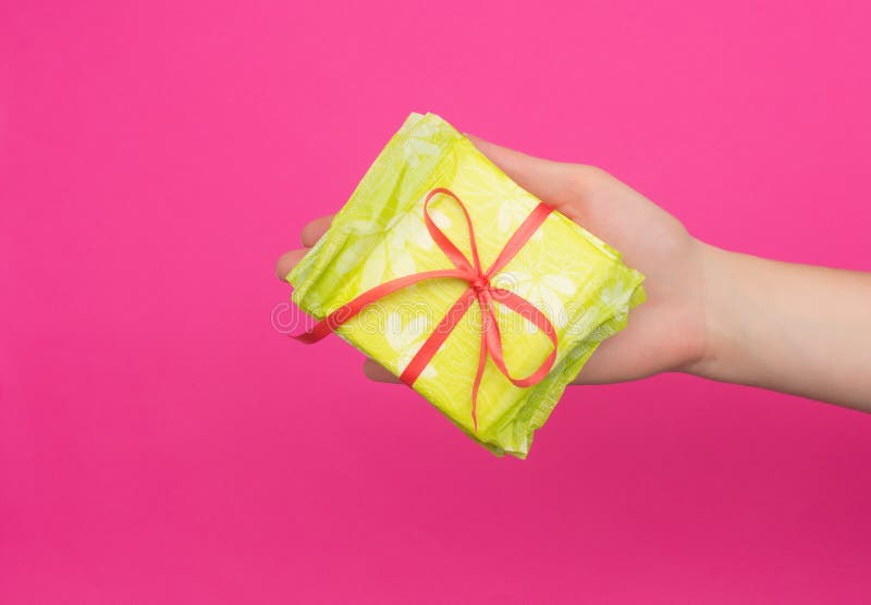 De vrouwelijke hand die een stapel sanitaire stootkussens houden bond met een rood lint in haar hand, roze achtergrond, kopieert royalty-vrije stock fotografie De vrouwelijke hand die een stapel sanitaire stootkussens houden bond met een rood lint in haar hand, roze achtergrond, kopieert royalty-vrije stock fotografie