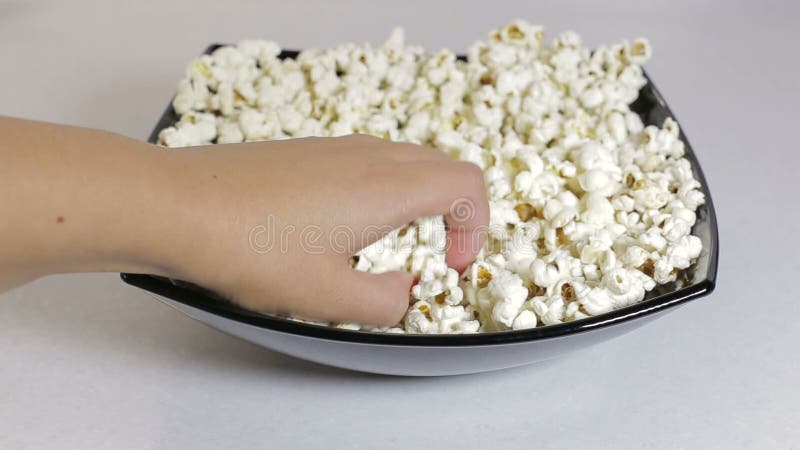 De vrouwelijke hand neemt de popcorn van een plaat