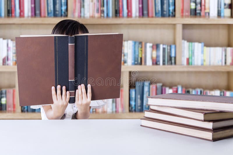 De vrouwelijke kleuterschoolstudent leest literatuur stock fotografie De vrouwelijke kleuterschoolstudent leest literatuur stock fotografie