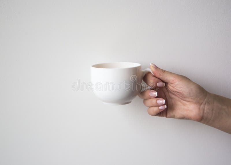 De vrouwelijke Kop van de Handholding van Koffie op Witte Muurachtergrond royalty-vrije stock foto De vrouwelijke Kop van de Handholding van Koffie op Witte Muurachtergrond royalty-vrije stock foto