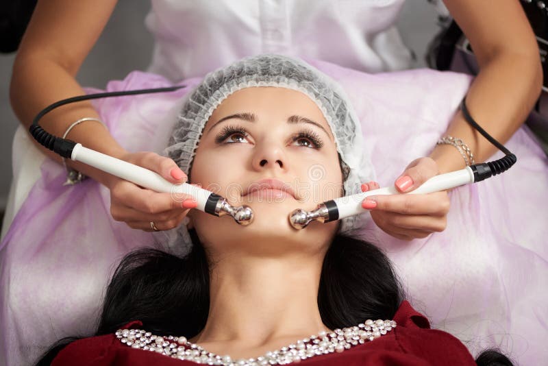 De vrouwelijke patiënt heeft gezichtsmassage in een schoonheidssalon De kosmetiek en de routine van de huidzorg stock foto's De vrouwelijke patiënt heeft gezichtsmassage in een schoonheidssalon De kosmetiek en de routine van de huidzorg stock foto's