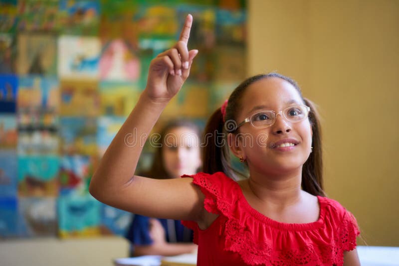 Leerling die haar hand opsteekt tijdens een toets in de klas op school stock foto