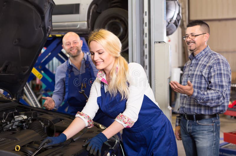 De vrouwelijke werktuigkundige bevestigt een auto royalty-vrije stock afbeelding De vrouwelijke werktuigkundige bevestigt een auto royalty-vrije stock afbeelding