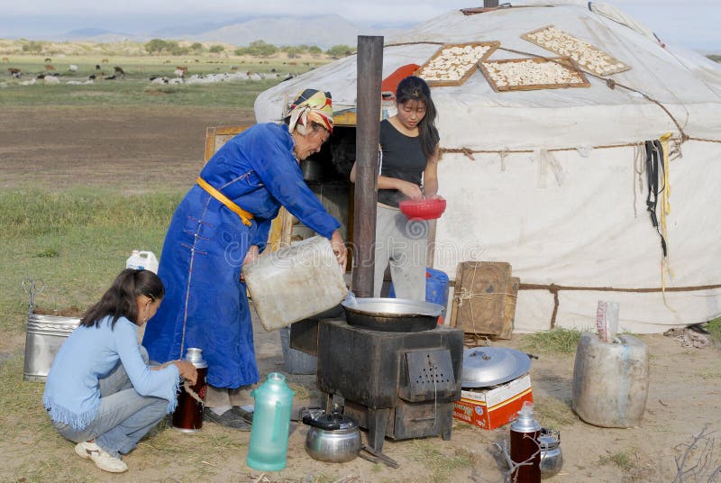 CIRCA HARHORIN, MONGOLIA - AUGUST 26, 2006: Unidentified women cook in front of the yurt entrance on August 26, 2006 circa Harhorin, Mongolia. Mongolian nomads relocate their tents 3-4 time a year to get enough grass for cattle and housekeeping in steppe for women is a hard task. CIRCA HARHORIN, MONGOLIA - AUGUST 26, 2006: Unidentified women cook in front of the yurt entrance on August 26, 2006 circa Harhorin, Mongolia. Mongolian nomads relocate their tents 3-4 time a year to get enough grass for cattle and housekeeping in steppe for women is a hard task.