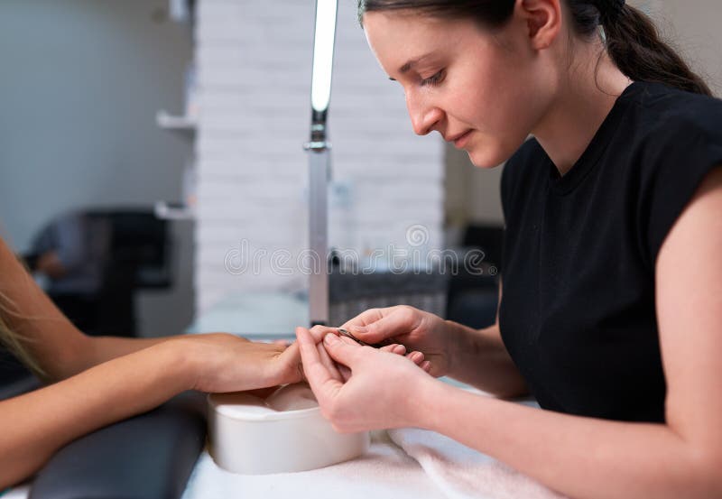 De vrouwenmanicure maakt opperhuid op de spijkers van cliënt in orde stock afbeeldingen De vrouwenmanicure maakt opperhuid op de spijkers van cliënt in orde stock afbeeldingen