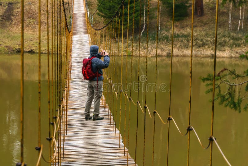 De vrouwenreiziger neemt een beeld van een hangbrug over de de lenterivier royalty-vrije stock foto De vrouwenreiziger neemt een beeld van een hangbrug over de de lenterivier royalty-vrije stock foto