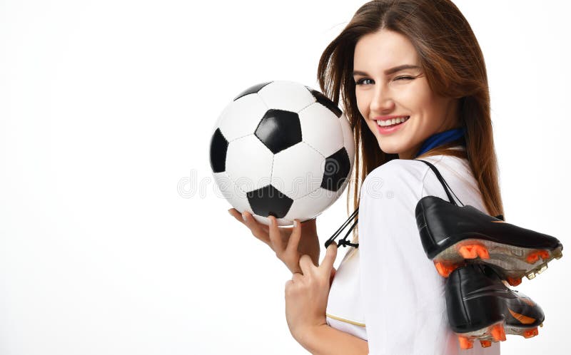 De vrouwenspeler van de ventilatorsport in de rode eenvormige bal van het greepvoetbal en laarzen vieren die op wit knipogen stock afbeelding De vrouwenspeler van de ventilatorsport in de rode eenvormige bal van het greepvoetbal en laarzen vieren die op wit knipogen stock afbeelding