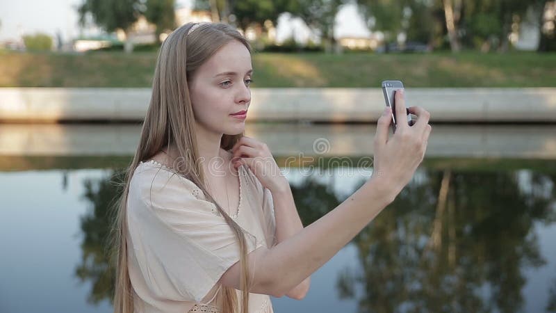 De vrouwenzitting in het park en maakt selfie, gelukkig Op de rivier