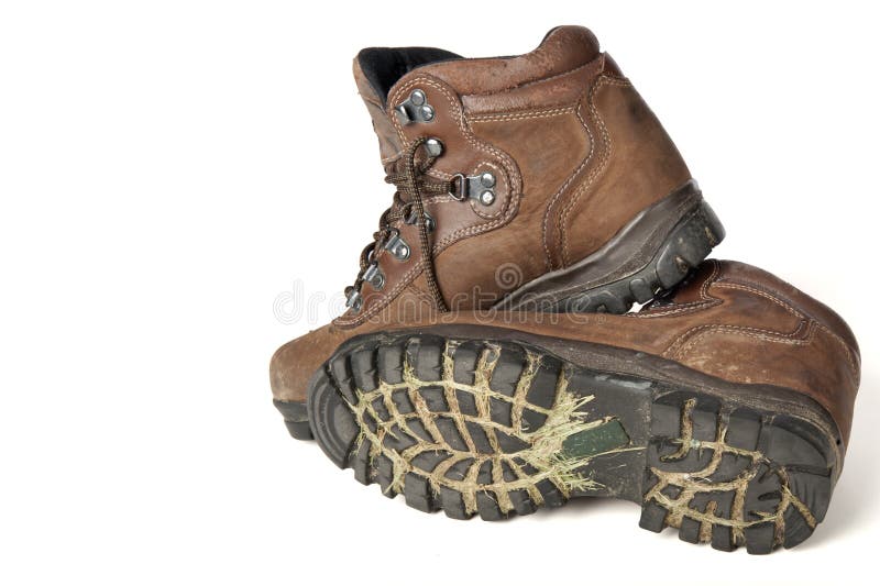 Dirty pair of hiking boots with grass and mud in the treads isolated on white. Dirty pair of hiking boots with grass and mud in the treads isolated on white