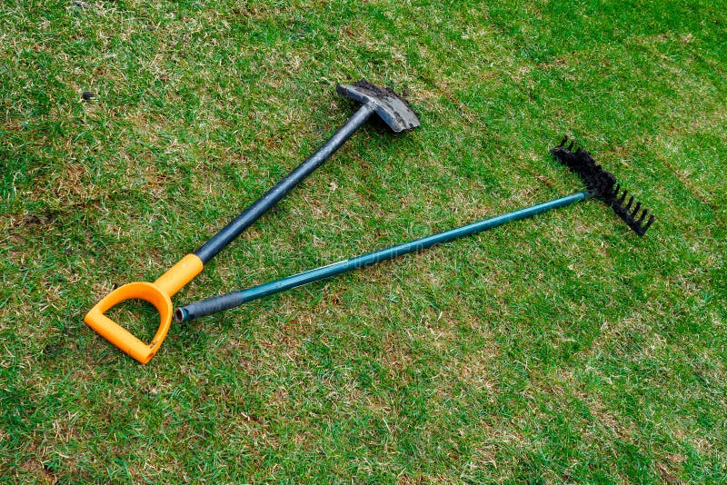 De vuile schop en de harken van de tuinman liggen op het verse gerolde gazon stock foto's De vuile schop en de harken van de tuinman liggen op het verse gerolde gazon stock foto's
